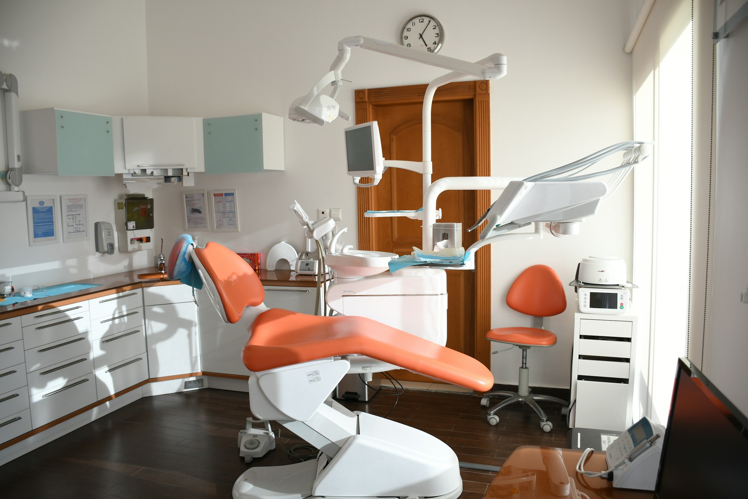 Bright dental operatory with a coral patient chair