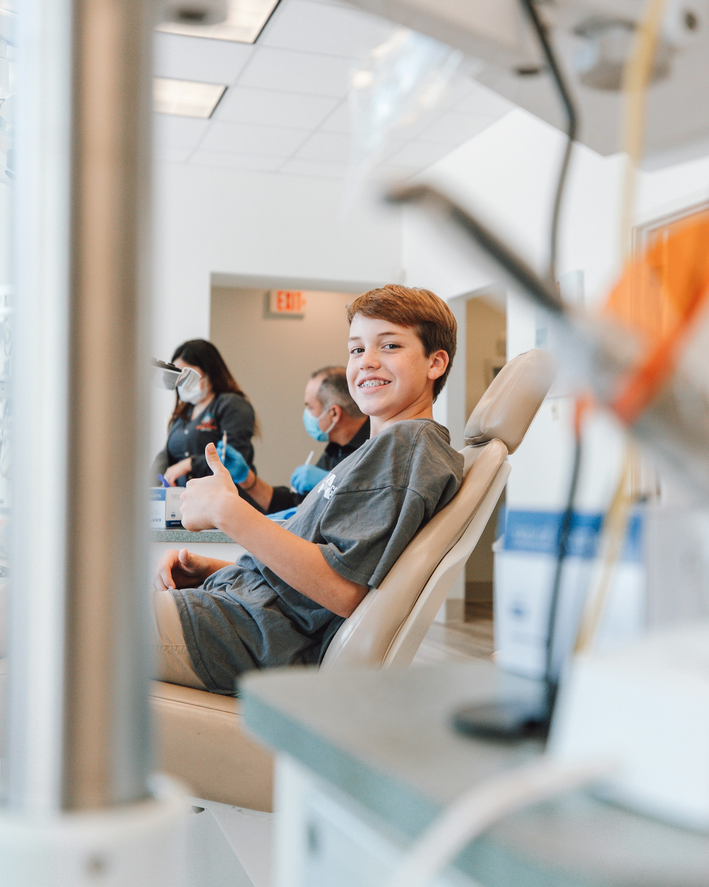 Smiling boy giving a thumbs up from a dental chair